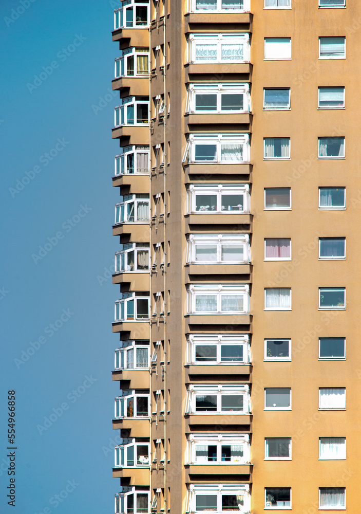 London, UK - March 26th 2022: Tall block of flats isolated against a blue sky background