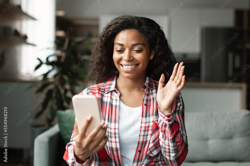 Smiling millennial black female blogger shoots vlog, has online video call, makes greeting gesture, waving hand Smiling millennial black female blogger shoots vlog, has online video call, makes greeting gesture, waving hand