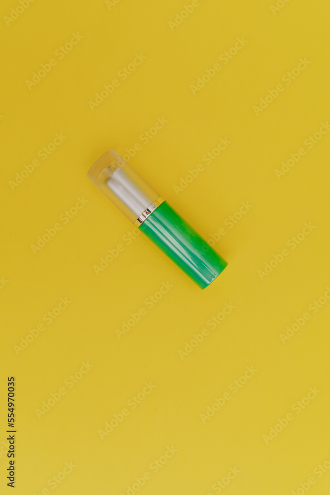 Lipstick with a bright green cap on a yellow background Lipstick with a bright green cap on a yellow background