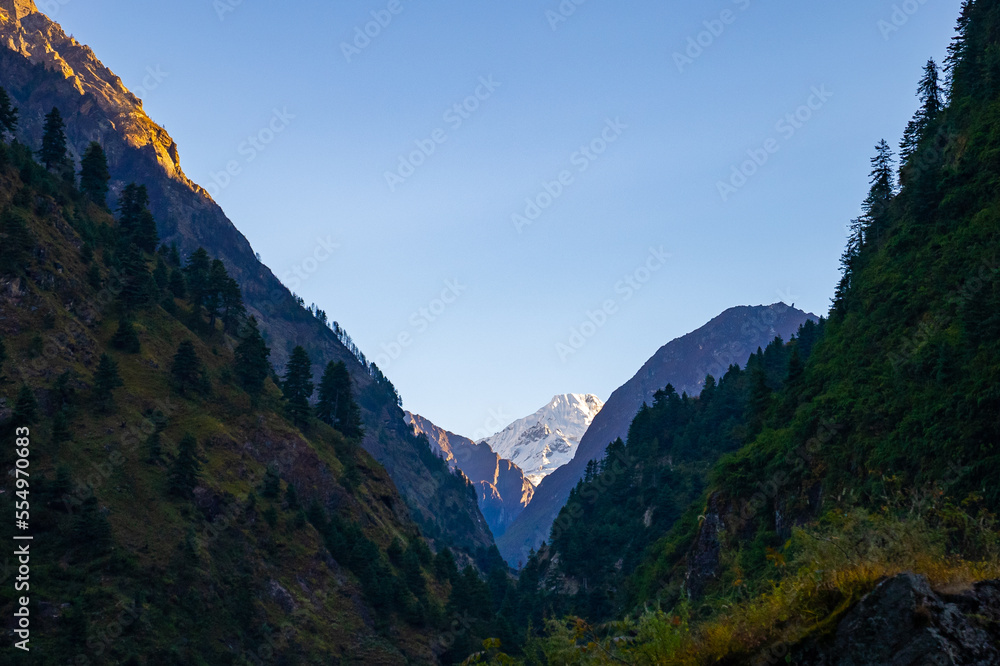 Snowy moutain peak in the sun with the hills and valleys in the shade along the Annapurna Circuit Trek, Nepal