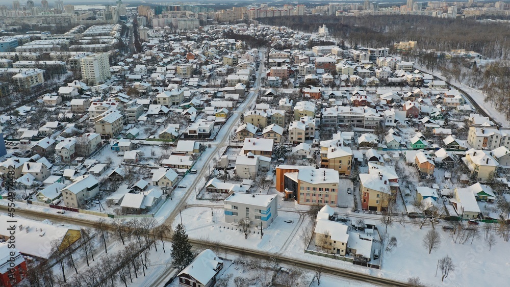 The private sector of a large major city in Europe in winter. Cottages, townhouses under a layer of snow. Snow on rooftops. Snowdrifts in the city.