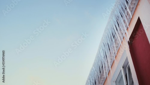 Large icicles hang from the overhang of the roof of the building. Falling ice- winter hazard for passersby photo