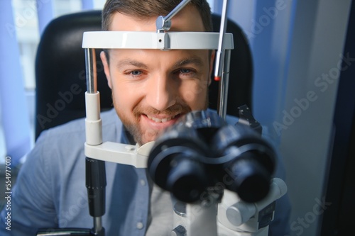 Fototapeta Naklejka Na Ścianę i Meble -  Handsome man getting an eye exam at ophthalmology clinic. Checking retina of a male eye close-up