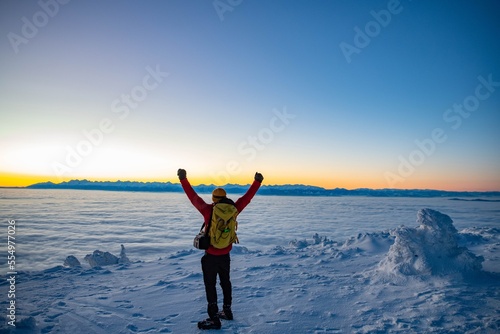 Obraz na płótnie Man climbs a mountain peak in winter during sunrise. Sunrise on Babia Gora with a view to the Tatra Mountains w salonie