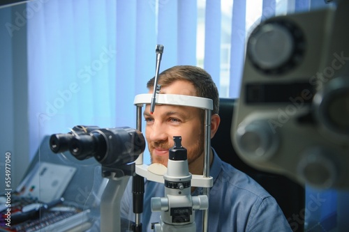 Handsome man getting an eye exam at ophthalmology clinic. Checking retina of a male eye close-up