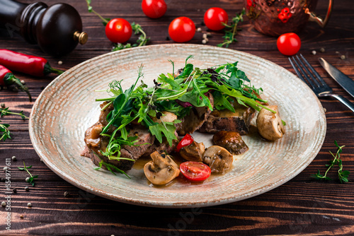 Dinner veal medallions with mushrooms, arugula, cherry tomatoes and sauce.