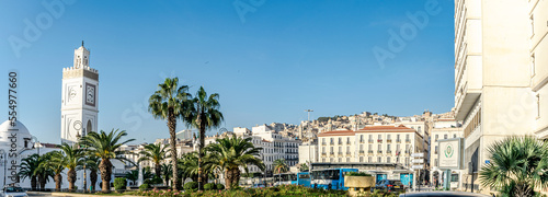 The old great mosque of Algiers. El Hadi Mghiref garden, busses parked at the Martyr's square bus station, El Aurassi hotel view between two palm trees and a clear blue sky in background. photo