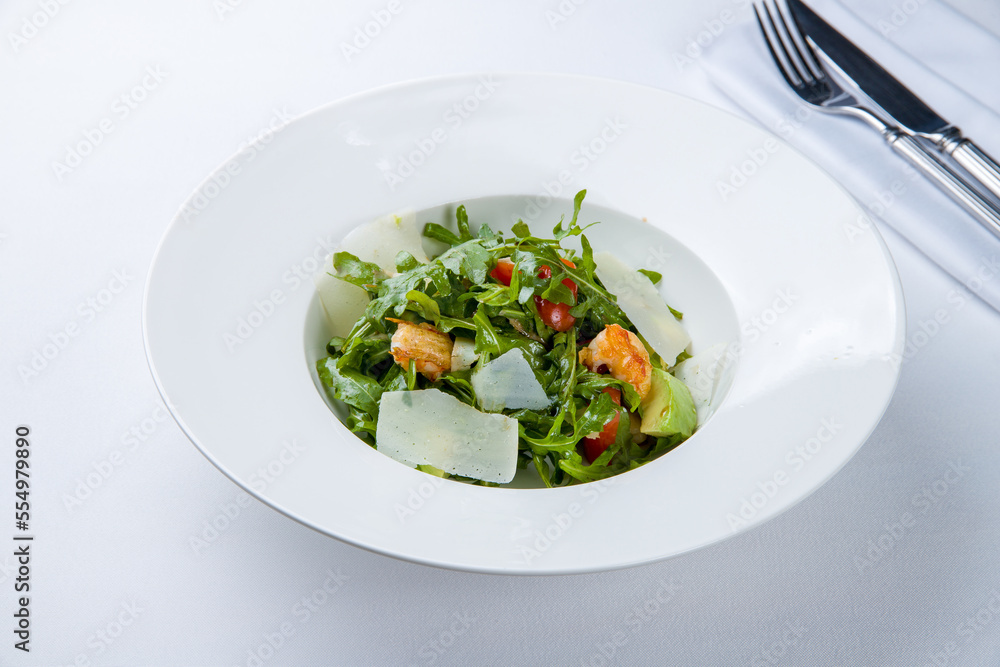 Arugula with shrimps and avocado on a white plate Arugula with shrimps and avocado on a white plate
