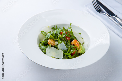 Arugula with shrimps and avocado on a white plate