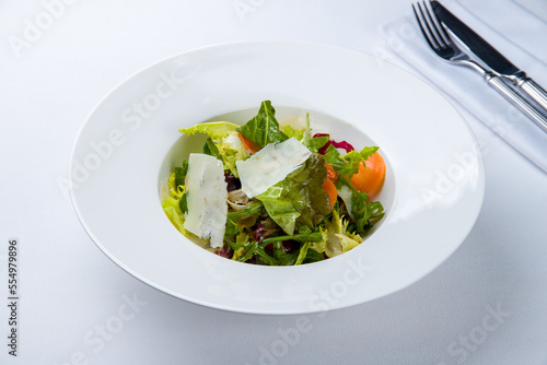 Green vegetable salad with parmesan on a white plate