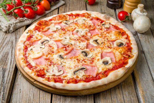 Pizza with ham and mushrooms with tomato sauce on wooden table, close up