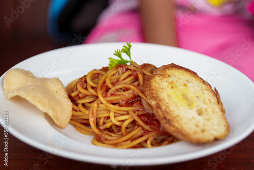 Delicious spaghetti with tomato sauce and vegetables served on a white plate
