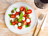 Fresh caprese salad with mozzarella, tomatoes, basil and pesto sauce on plate