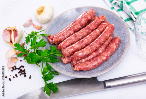 Raw sausages longaniza prepared for barbecue on plate. Traditional Catalan meat products