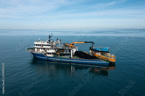 Fishing boat aerial view from drone on sea surface. Fishing and seafood industry.