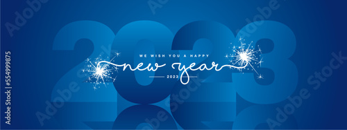 We wish you Happy New Year 2023, modern design, white new updated handwritten lettering with blue 2023 year mirrored shadow in background and sparkler firework