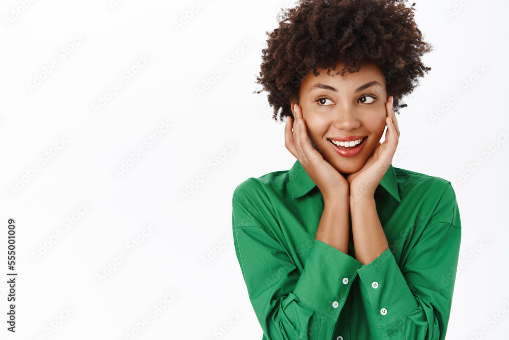 Beauty. Smiling Black young woman with curly hair, smiling, looking silly and cute, daydreaming, feeling excitement over smth, white background Beauty. Smiling Black young woman with curly hair, smiling, looking silly and cute, daydreaming, feeling excitement over smth, white background