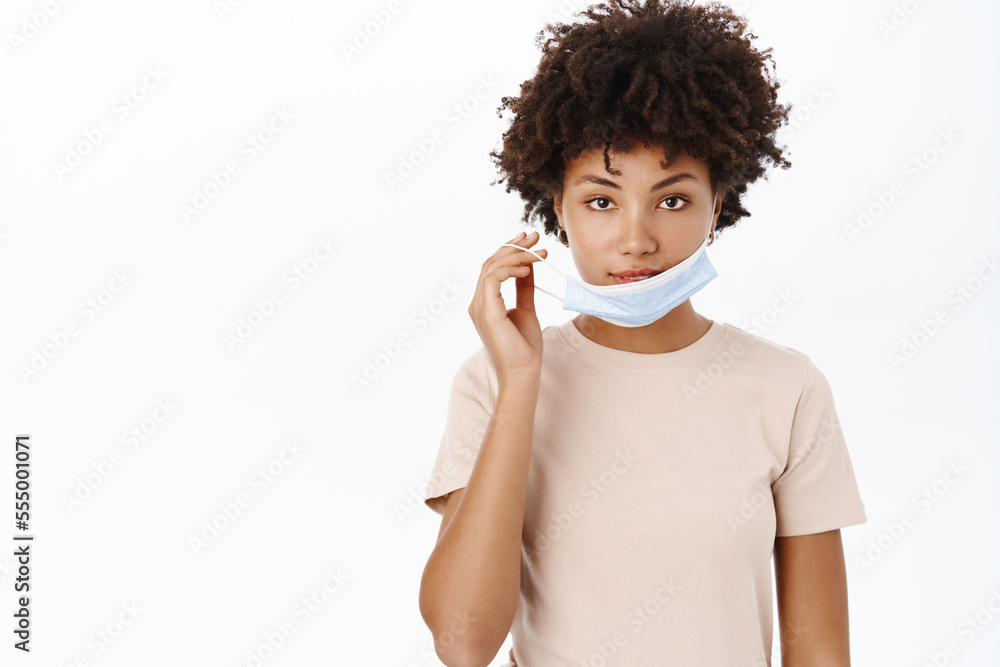 Covid 19 and health concept. Young Black woman wearing medical face mask on quarantine, self-isolation during coronavirus, flu outbreak, white studio background Covid 19 and health concept. Young Black woman wearing medical face mask on quarantine, self-isolation during coronavirus, flu outbreak, white studio background