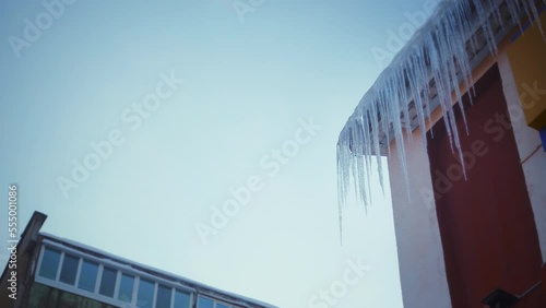 Large icicles hang from the overhang of the roof of the building. Falling ice- winter hazard for passersby