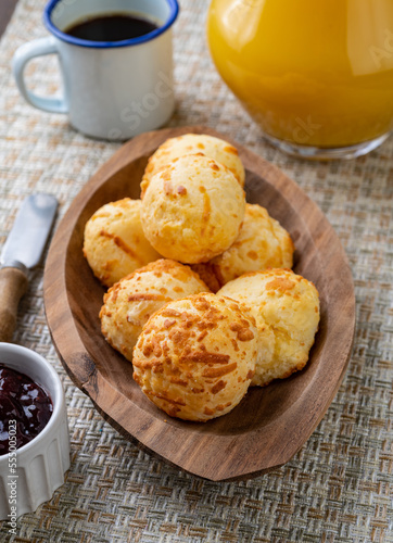 Typical brazilian cheese bun in a plate with coffee, jam and orange juice over wooden table