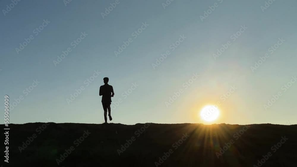 Skinny young man exercising jogging in place at sunrise. Silhouette wide static slow motion shot Skinny young man exercising jogging in place at sunrise. Silhouette wide static slow motion shot