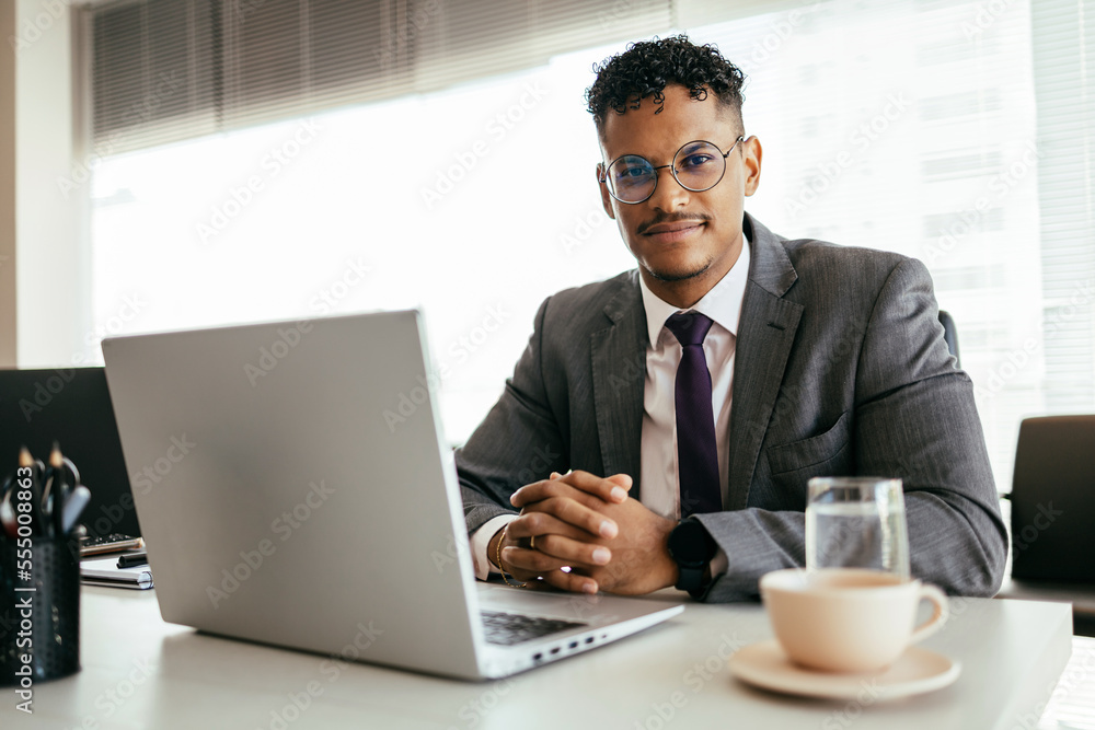Young Brazilian businessman working on laptop in modern office Young Brazilian businessman working on laptop in modern office