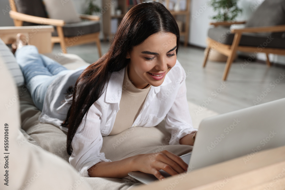 Young woman working with laptop on sofa at home Young woman working with laptop on sofa at home