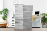 Stacked sheets of paper on wooden table in office