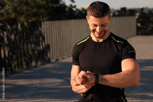 Fototapeta Attractive happy man checking pulse after training outdoors
