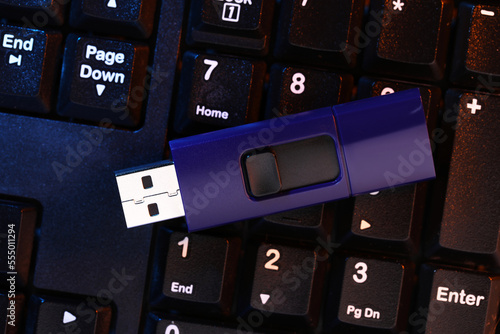 Modern usb flash drive on computer keyboard, top view photo