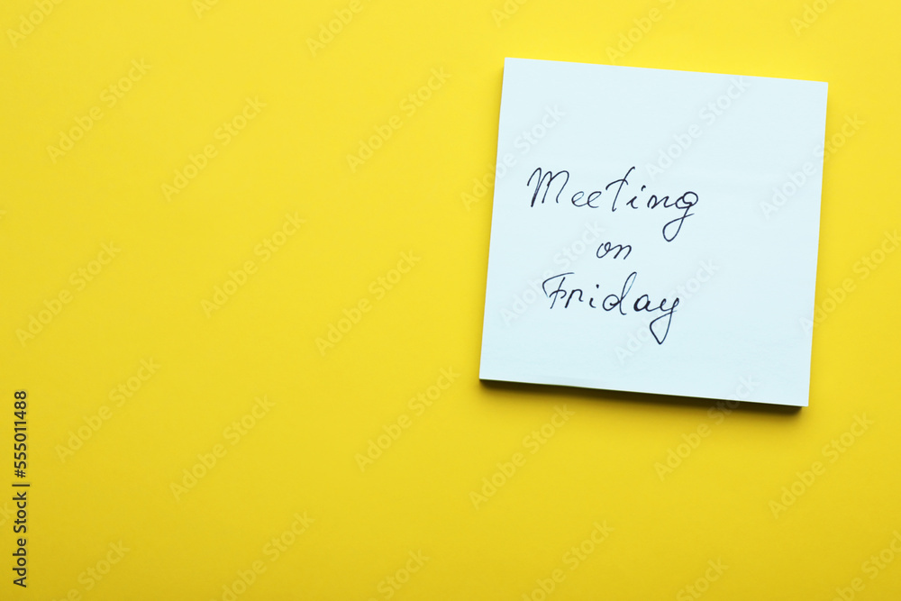 Paper note with words Meeting on Friday against yellow background, top view. Space for text Paper note with words Meeting on Friday against yellow background, top view. Space for text