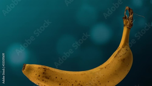 view of a ripe banana against a blue bokeh background. rotative close-up photo