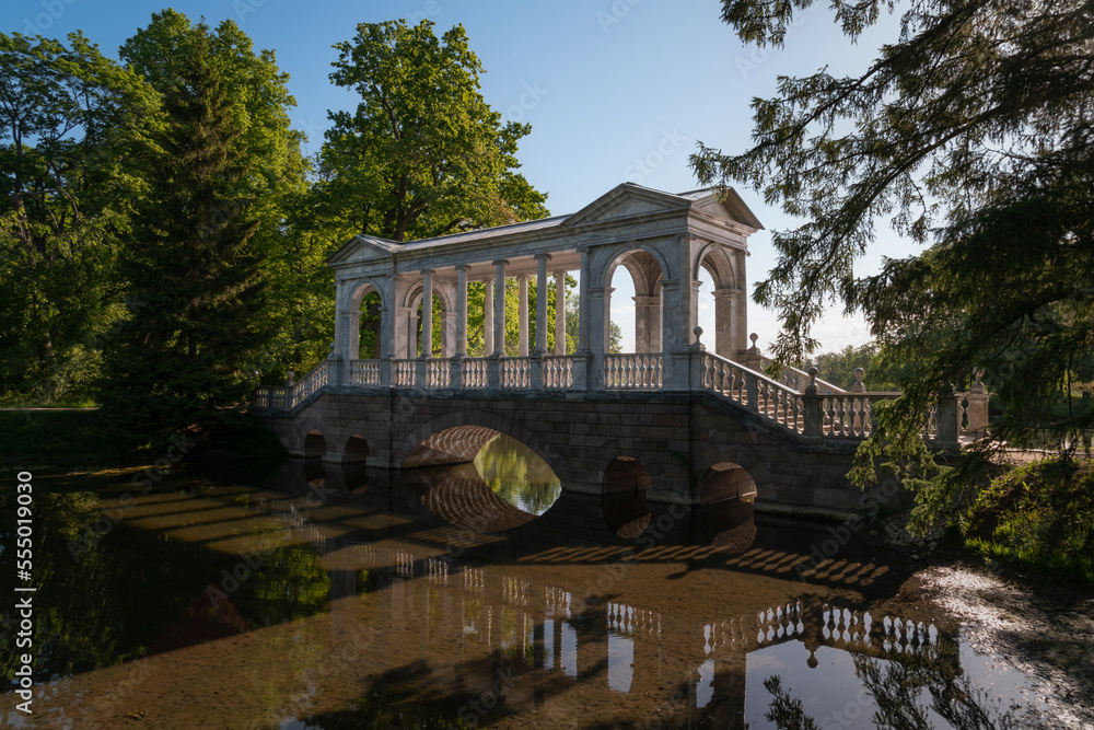 Marble bridge on the shore of a Large pond in the Catherine Park in Tsarskoye Selo on a sunny summer day, Pushkin, St. Petersburg, Russia