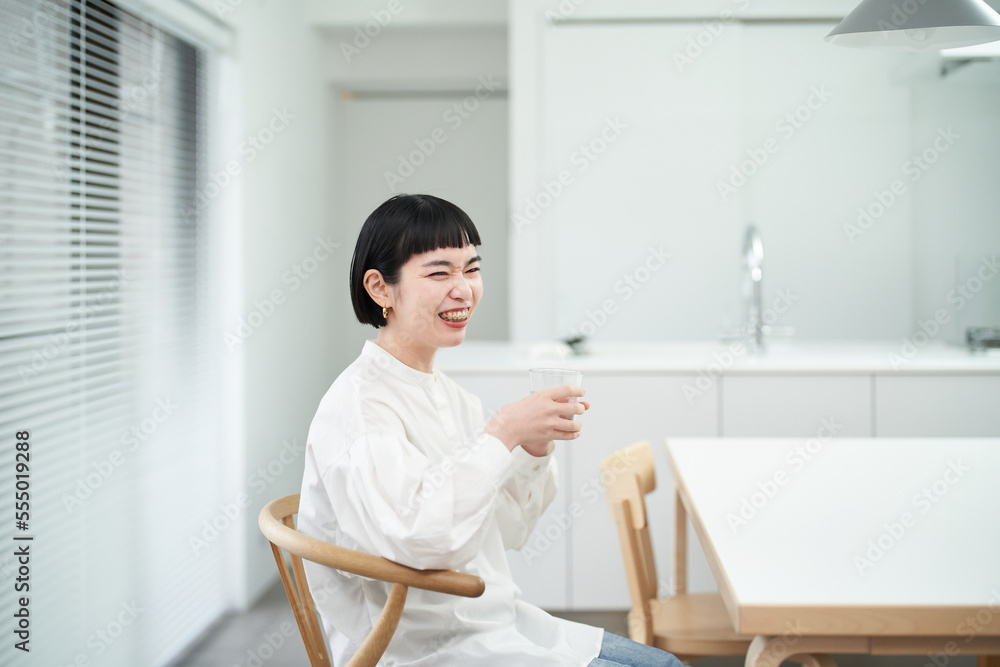 落ち着いた部屋で水を飲む若い女性 落ち着いた部屋で水を飲む若い女性