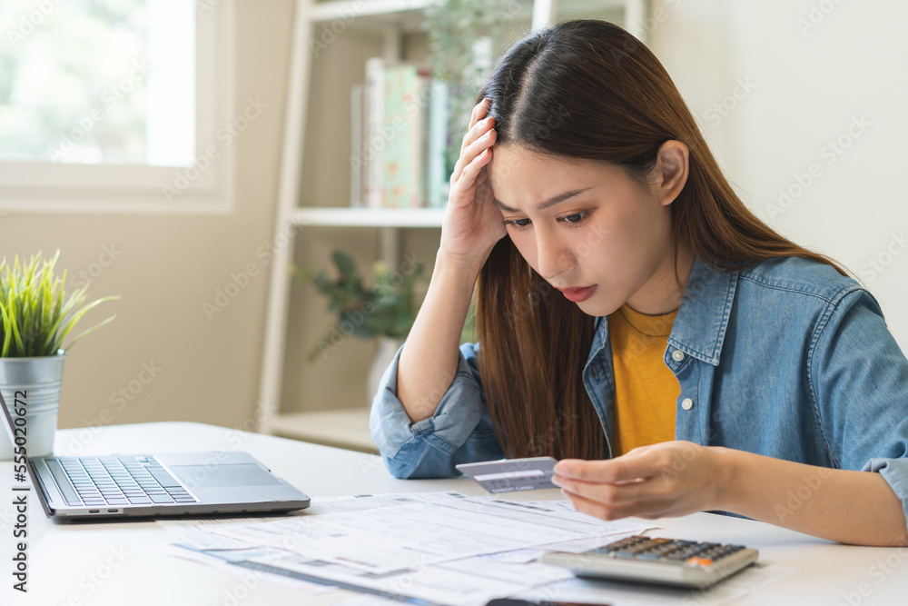 Financial owe, hand of asian woman sitting, holding credit card, stressed by calculate expense from invoice or bill, no money to pay, mortgage or loan. Debt, bankruptcy or bankrupt. Financial owe, hand of asian woman sitting, holding credit card, stressed by calculate expense from invoice or bill, no money to pay, mortgage or loan. Debt, bankruptcy or bankrupt.