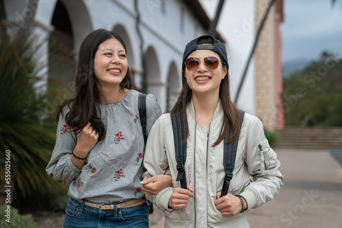 closeup of two cheerful asian korean college girls spending spring holiday together visiting historic old mission santa Barbara in California usa