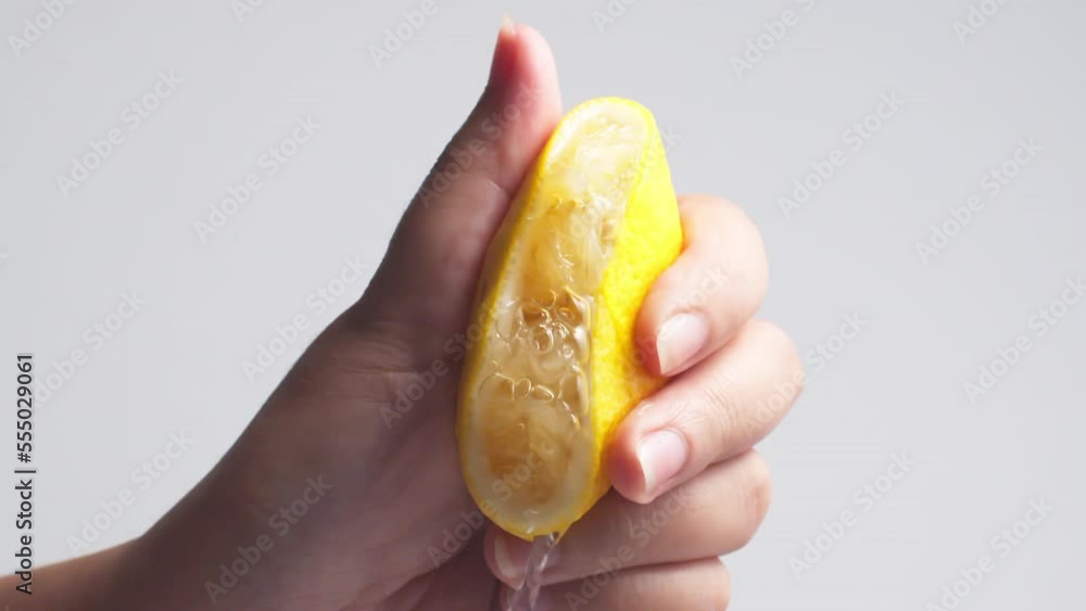 Hand squeezes lemon juice on a white background, isolated Hand squeezes lemon juice on a white background, isolated