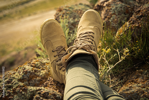 High laced hiking shoes on female legs in rocky terrain safari style.