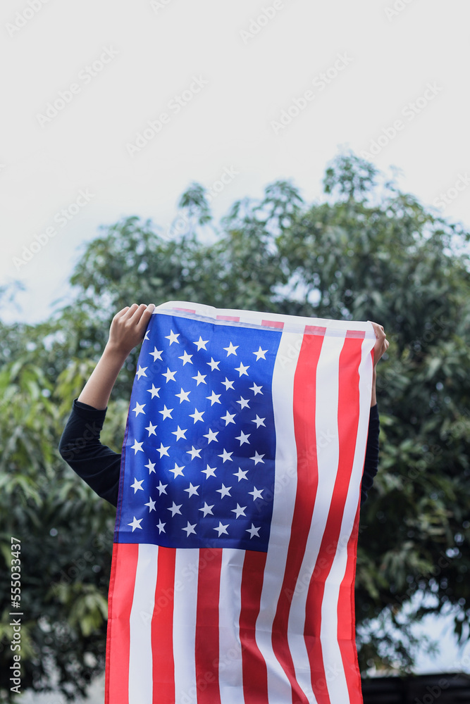 Young woman stands and holds an American flag outdoors