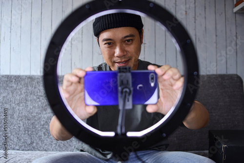 Asian vlogger man preparing equipment for live broadcasting, setting mobile phone before recording.