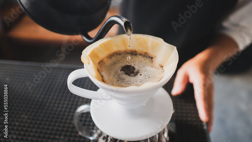 Hand Drip Coffee, Barista pouring hot water on roasted coffee ground with filter,and man is pouring hot coffee from the coffee pot into the white cup coffee on the table in the morning,vintage