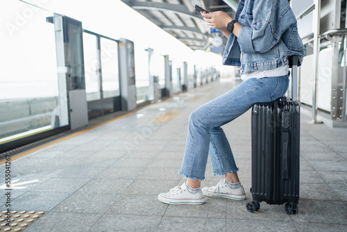 Woman sitting on the bag and waiting at the platform in sky train station.