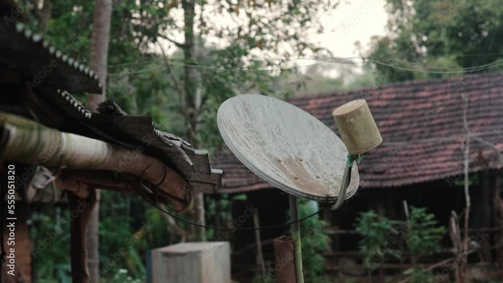 Outdoor satellite dish on top of wooden house roof in rural area Outdoor satellite dish on top of wooden house roof in rural area