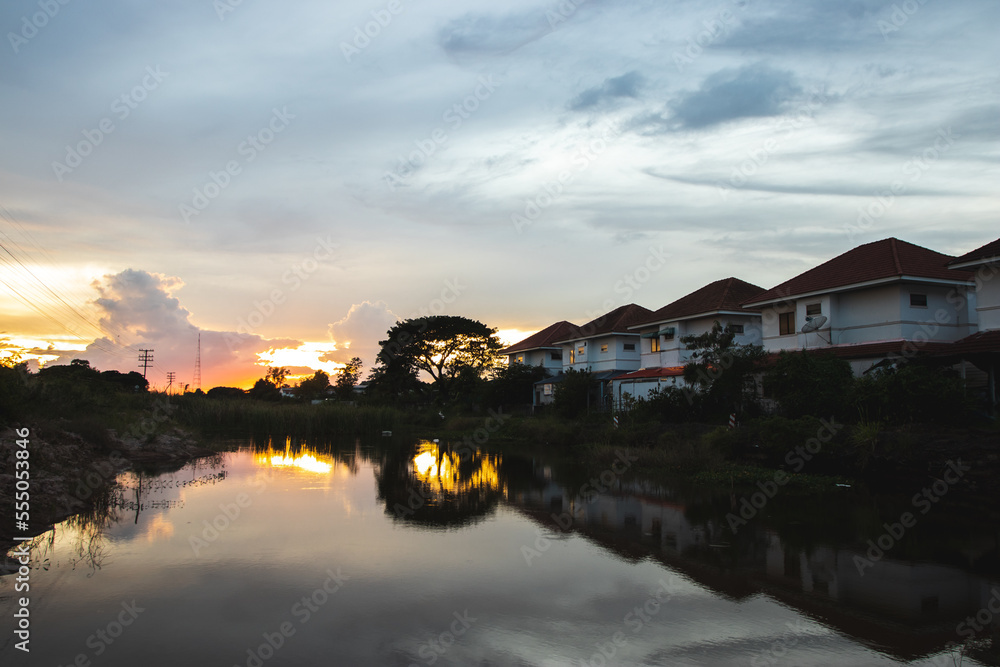 NAKHON RATCHASIMA, THAILAND - OCT27, 2022: Row of the houses reflected in the shadow of the water with sunset in Nakhon Ratchasima , Thailand. Property and real estate. NAKHON RATCHASIMA, THAILAND - OCT27, 2022: Row of the houses reflected in the shadow of the water with sunset in Nakhon Ratchasima , Thailand. Property and real estate.