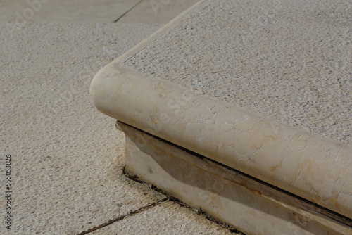 low riser comfortable exterior stair of one riser. deteriorating joints. soft beige color lime stone with texture. abstract architectural design. outdoors. exterior detail. background image photo