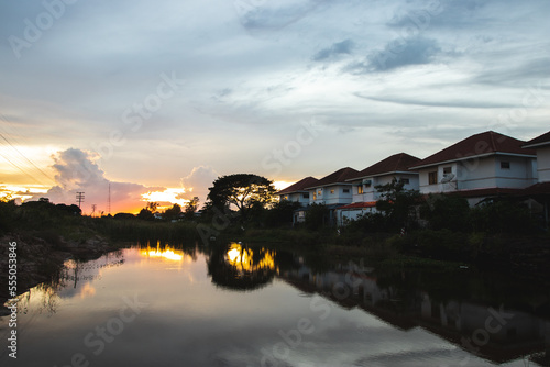 NAKHON RATCHASIMA, THAILAND - OCT27, 2022: Row of the houses reflected in the shadow of the water with sunset in Nakhon Ratchasima , Thailand. Property and real estate. © kannapon