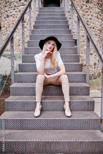 Blonde woman sitting while posing outdoors