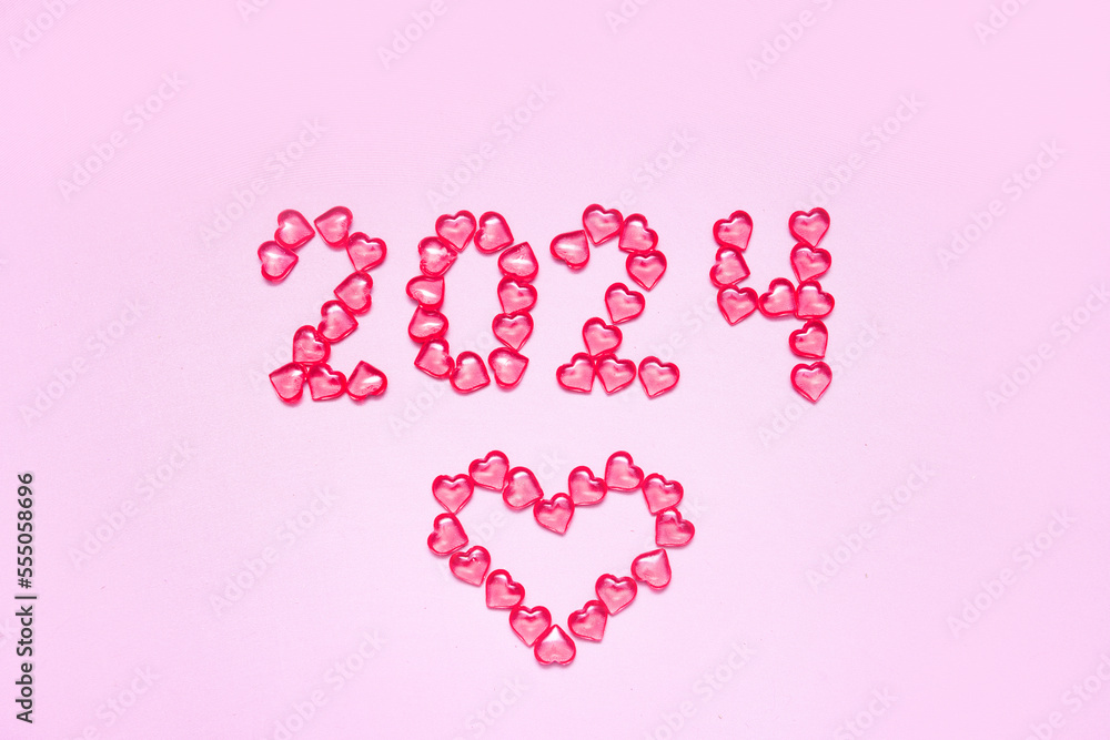 New Year 2023 inscription from glass hearts on a pink background. Pantone color 2023. Idea and creativity. Valentine's Day. Christmas with loved ones. Horizontally, banner. High quality photo