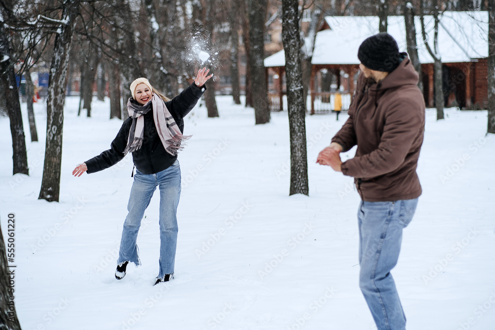 Valentines day outdoors celebration date ideas. Winter love story. Cold season dating for couples. Young couple in love play snowball, hugging and kissing in winter city street and park