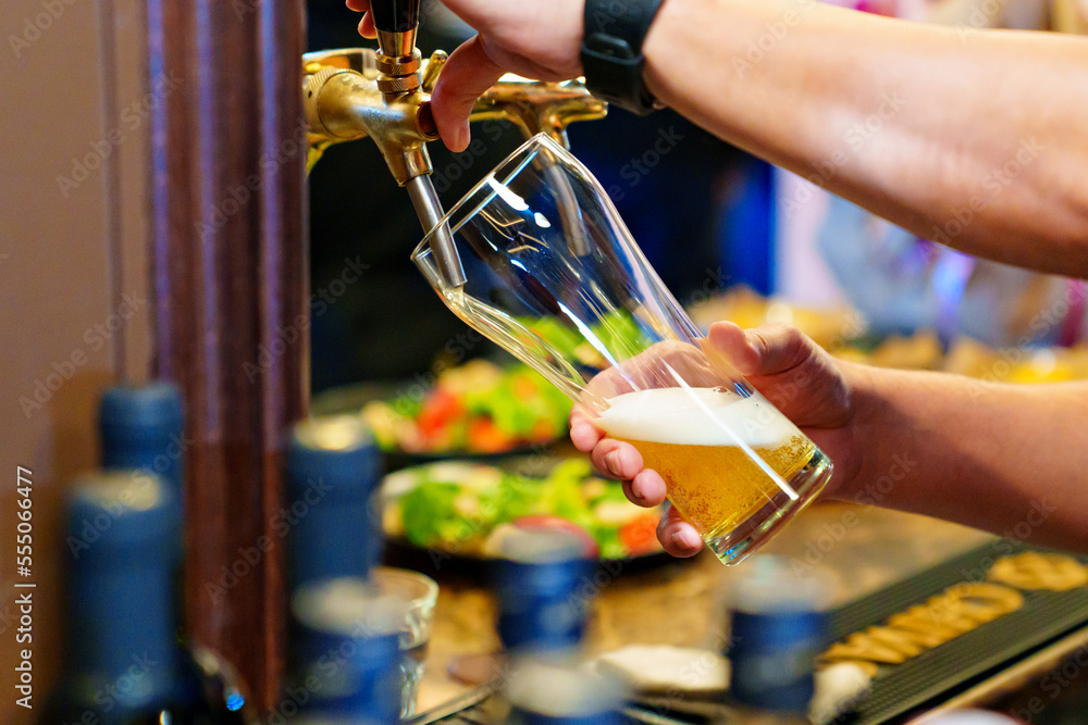 men's hands pour beer into a beer tap glass.